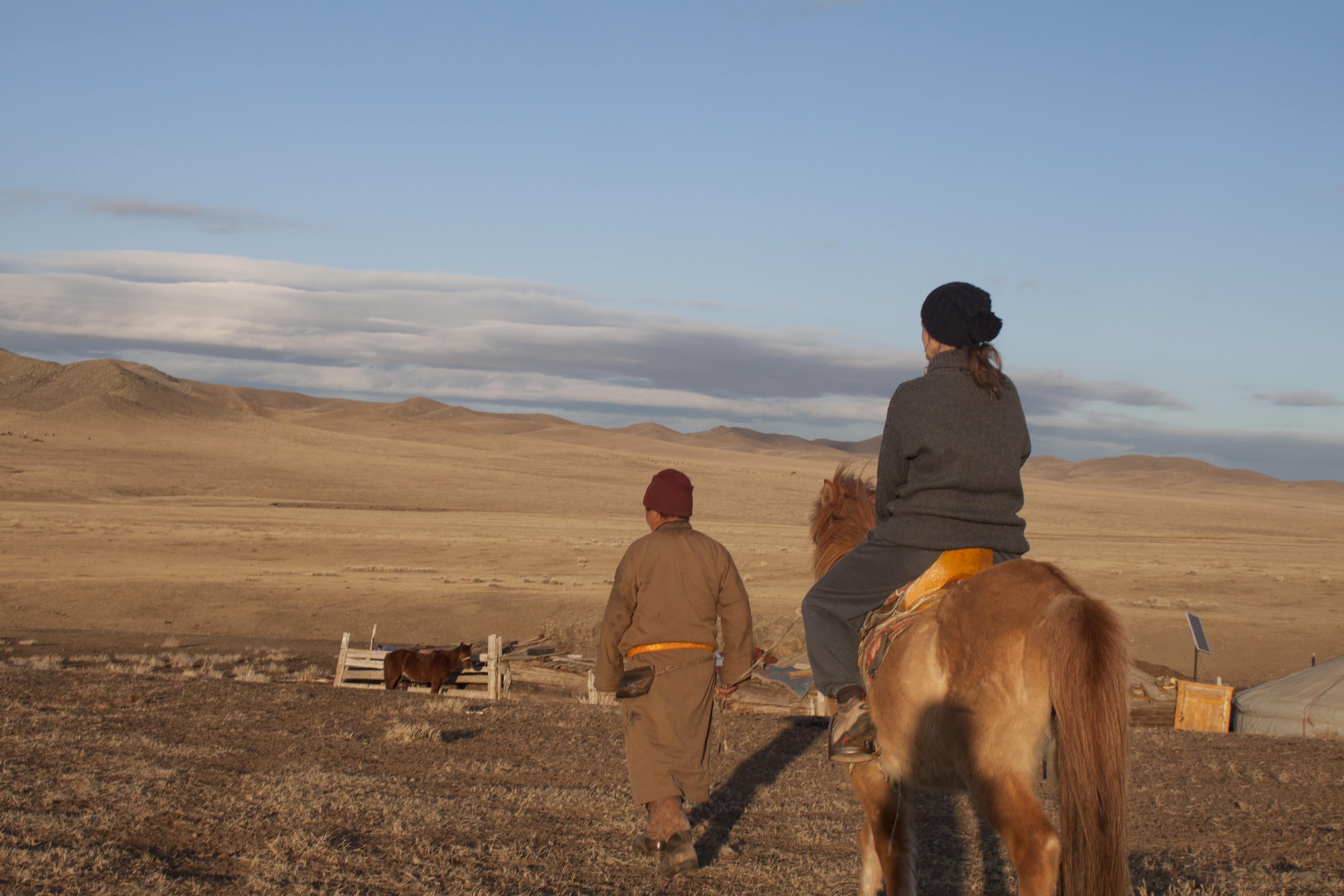 Two people from a local nomadic tribe attend to livestock on Mongolian Steppe, Asia.  Nomads living on the Mongolian Steppe take care of their farm animals.