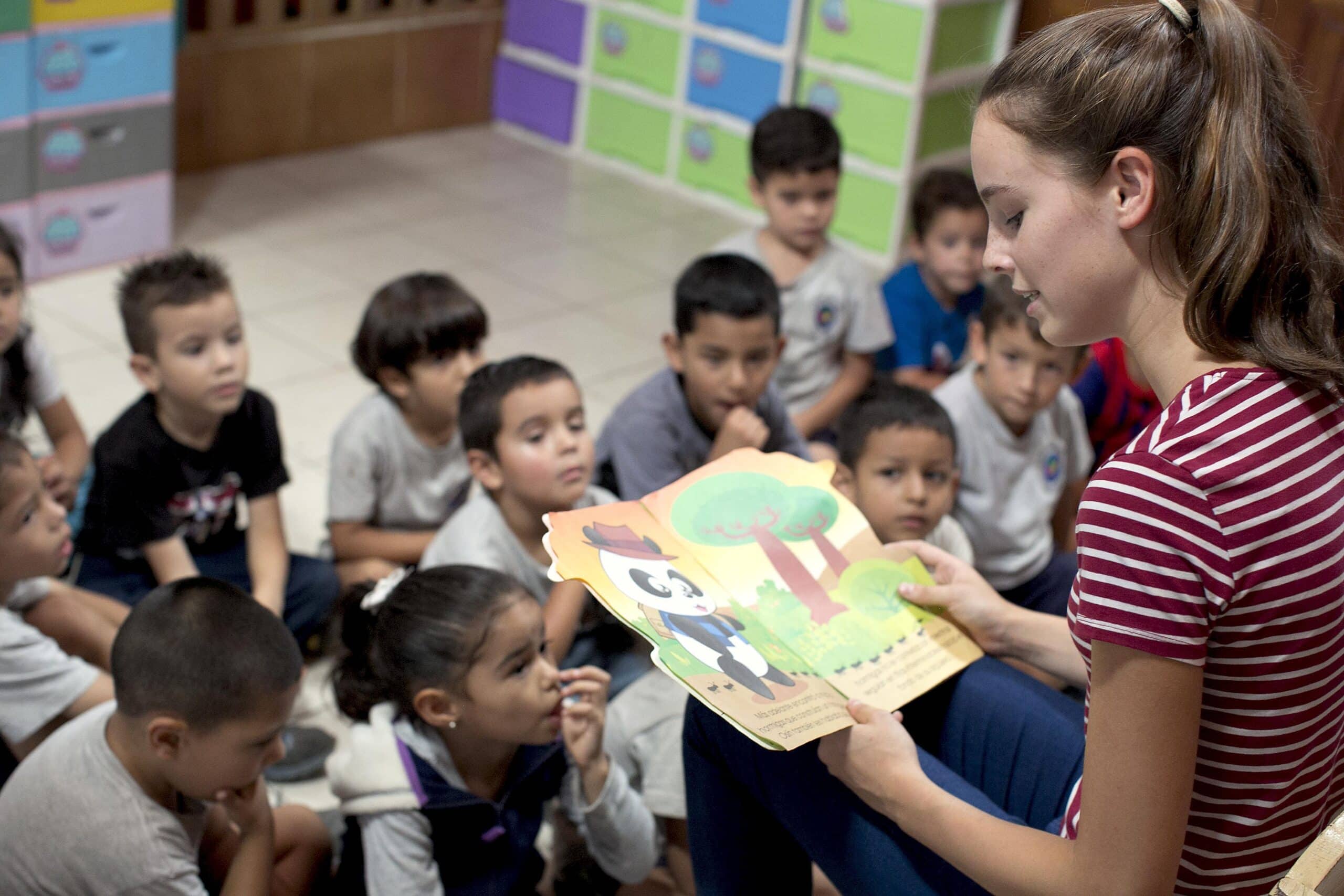 Childcare and Conservation volunteer reads a story to the children in her class