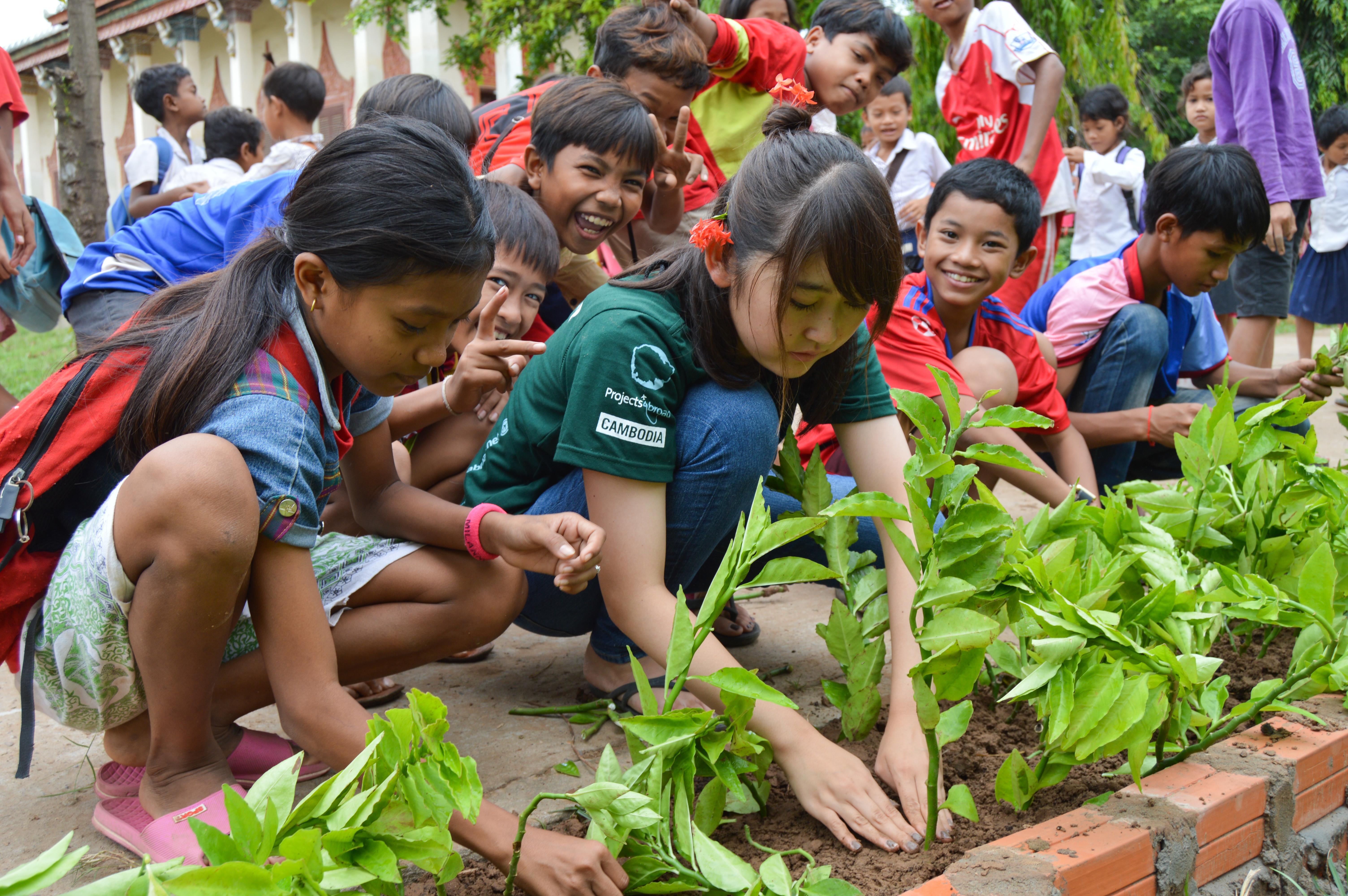 A volunteer on a short volunteer trip abroad helps put plants in the flowerbed A short term volunteer planting flowers