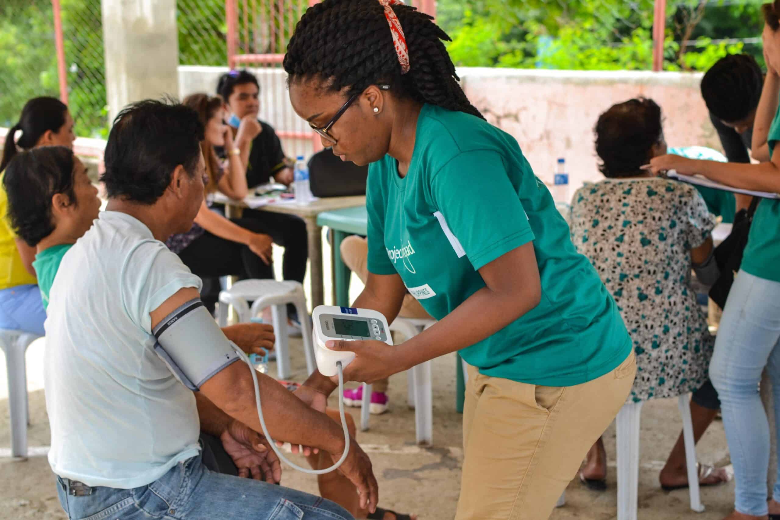 A short term volunteer abroad taking blood pressure during a medical outreach A Public Health volunteer takes the blood pressure of a local man during a medical outreach