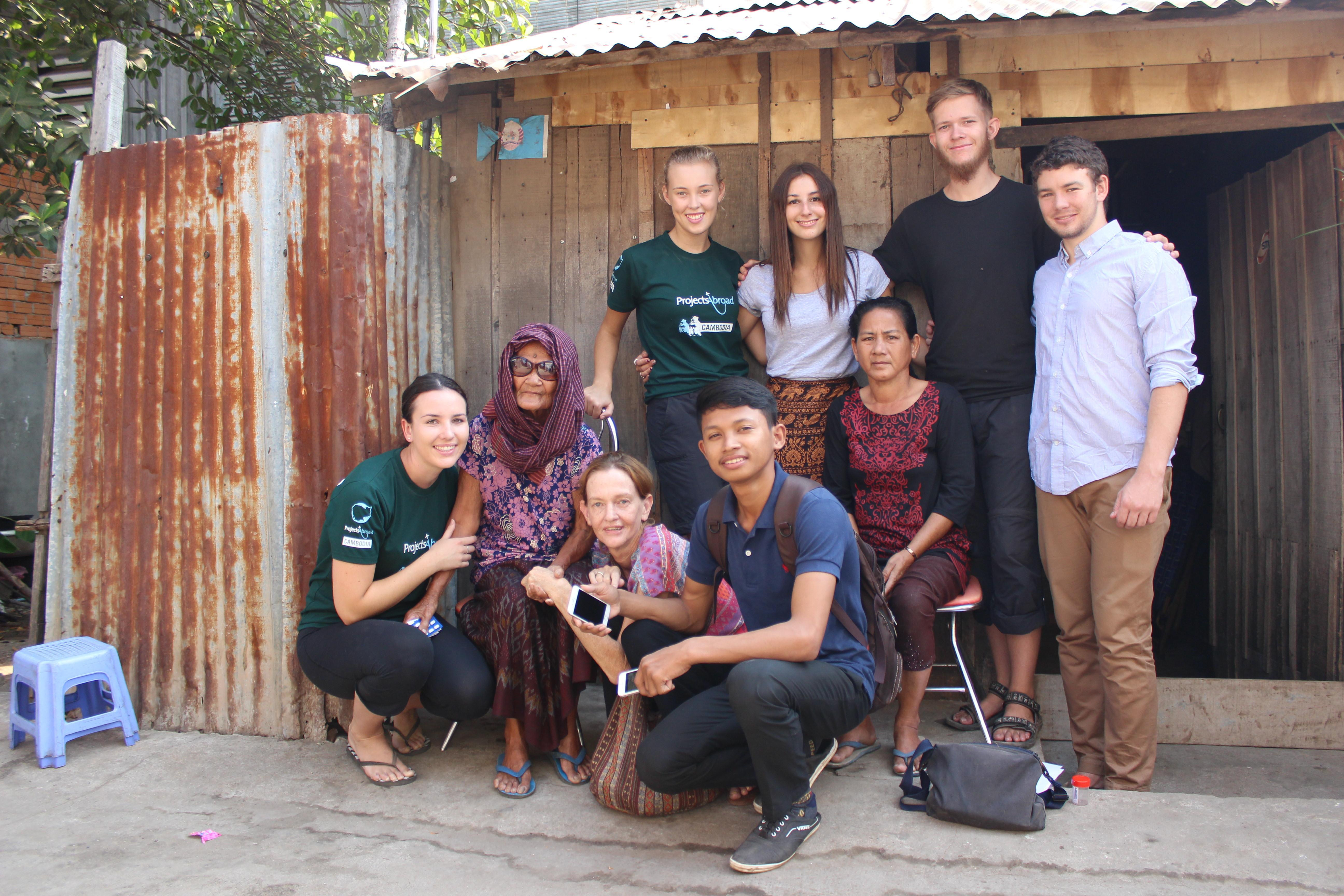 A local family with a group of volunteers outside their home Volunteers take a group photo with a local family during their time abroad
