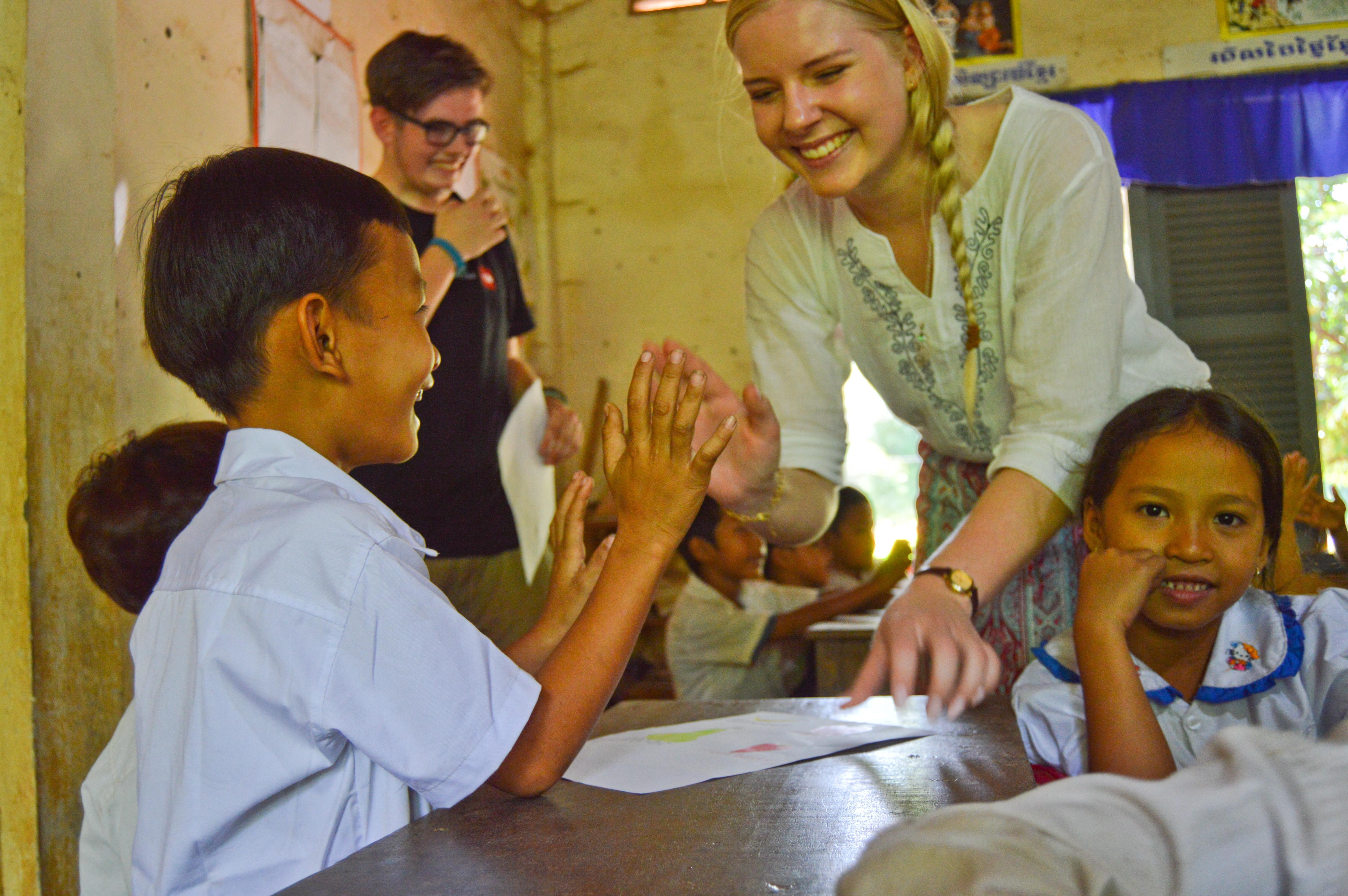 A Cambodian boy high-fives a high school volunteer during a class activity A high school volunteer plays a game with a young boy during her class in Cambodia