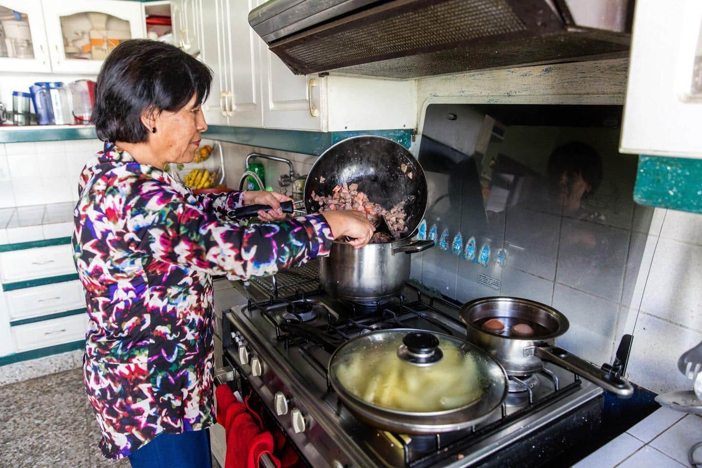 A host mother cooks a traditional meal for her volunteers abroad.  Volunteers receive home cooked meals during their time with their host families abroad.