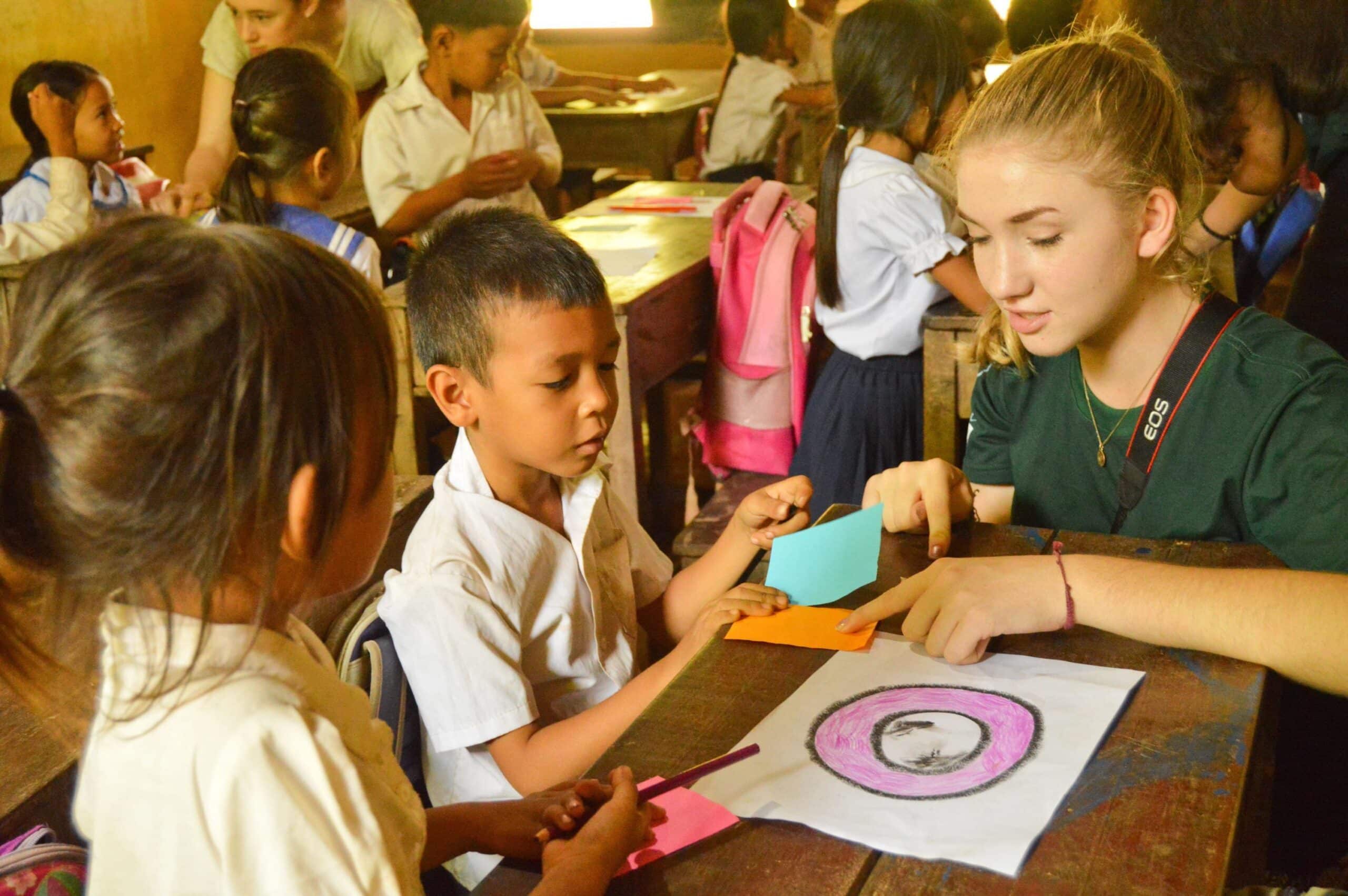 Childcare volunteer teaches a young boy different colours during school in Cambodia