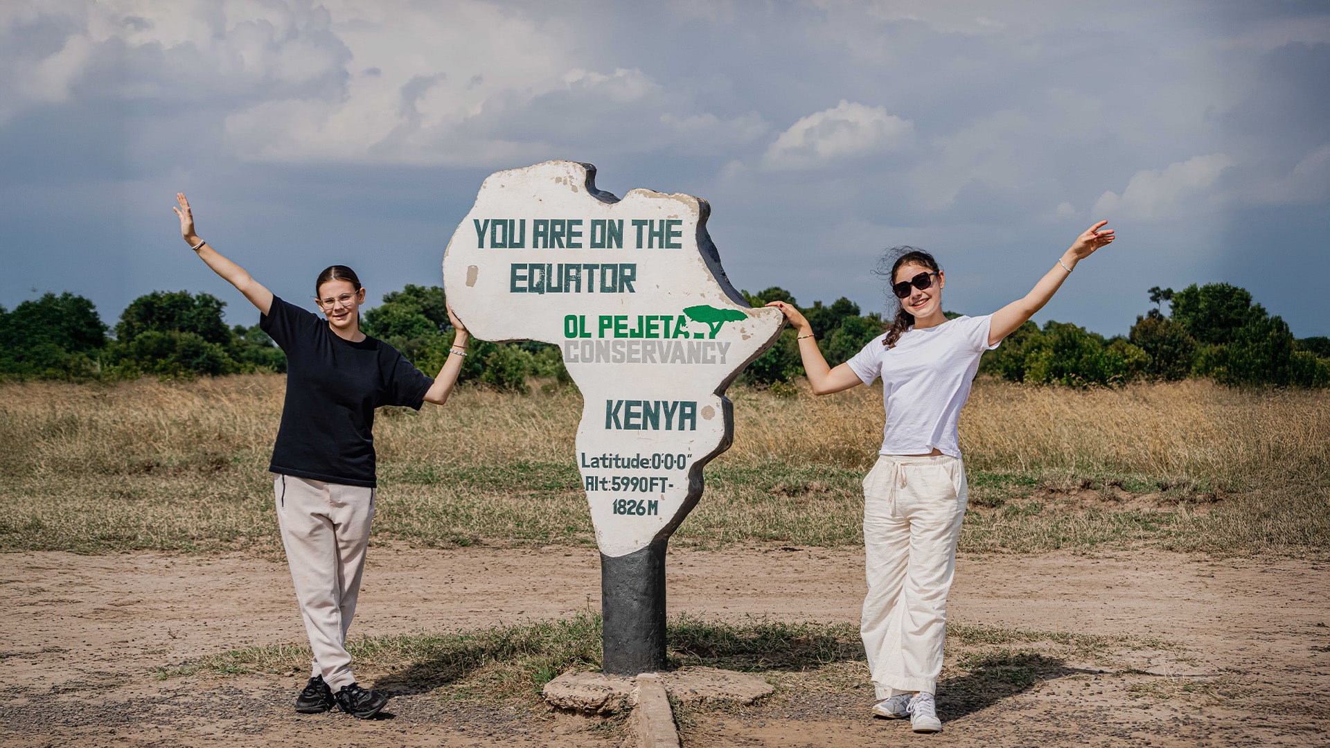 Girls standing by equator sign kenya