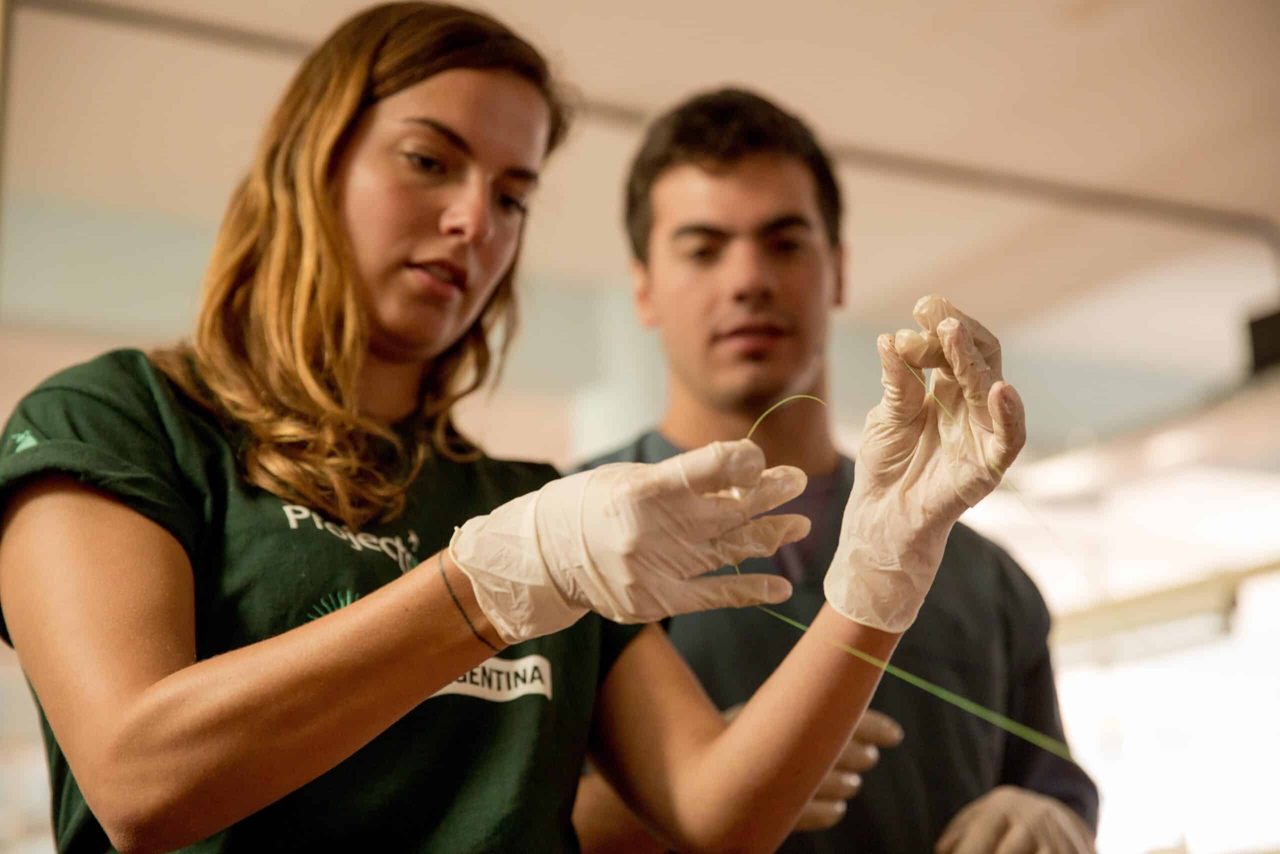 Female Projects Abroad Medicine intern learns how to tie a sature at a hopsital as part of her medical work experience in Argentina.