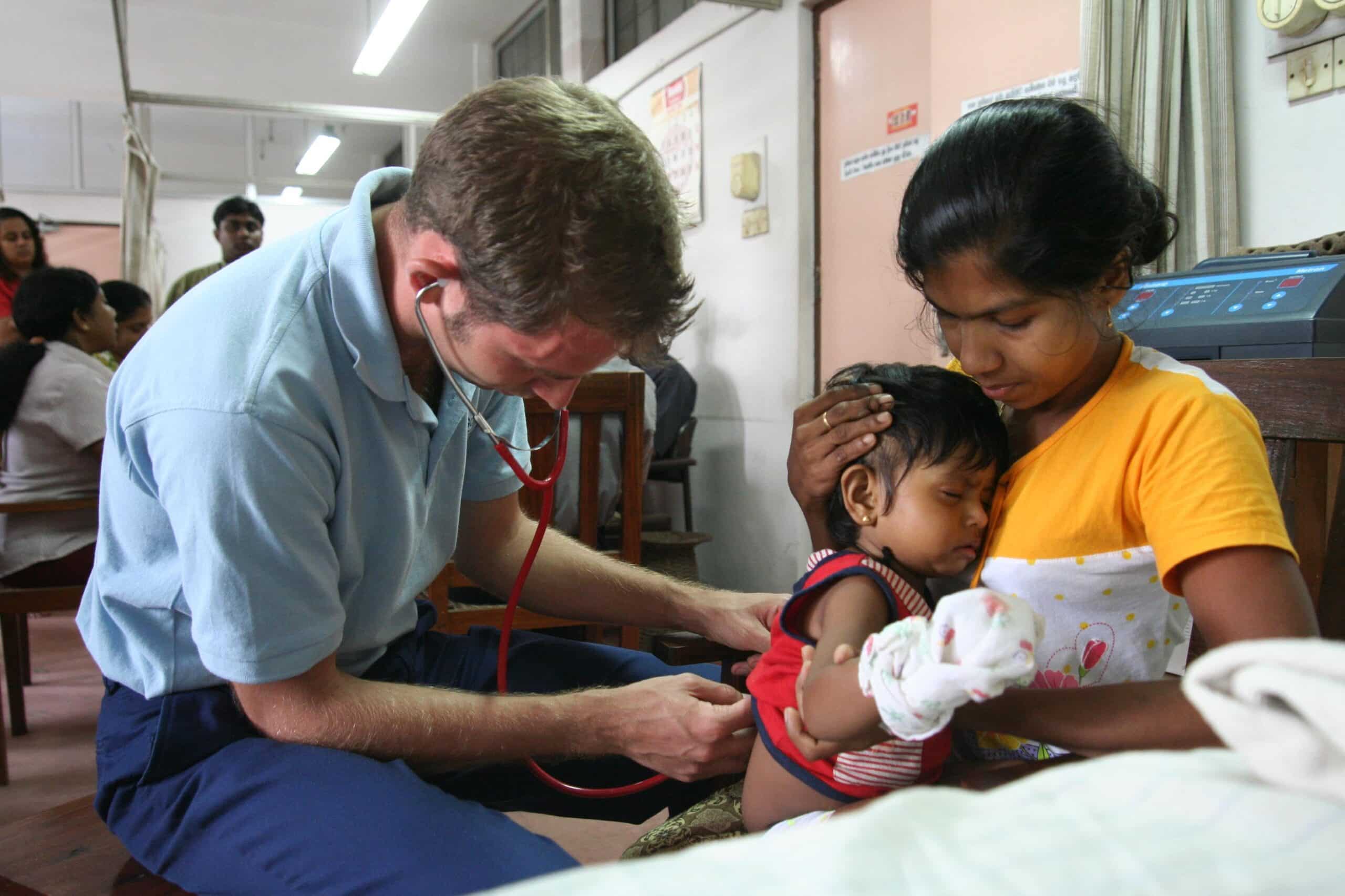 Male Projects Abroad intern giving a baby a check up whilst on his nursing internship in Sri Lanka where there are lots of nursing internship oppurtunities.