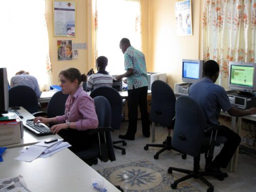A volunteer teaching computer skills to a student in Ghana
