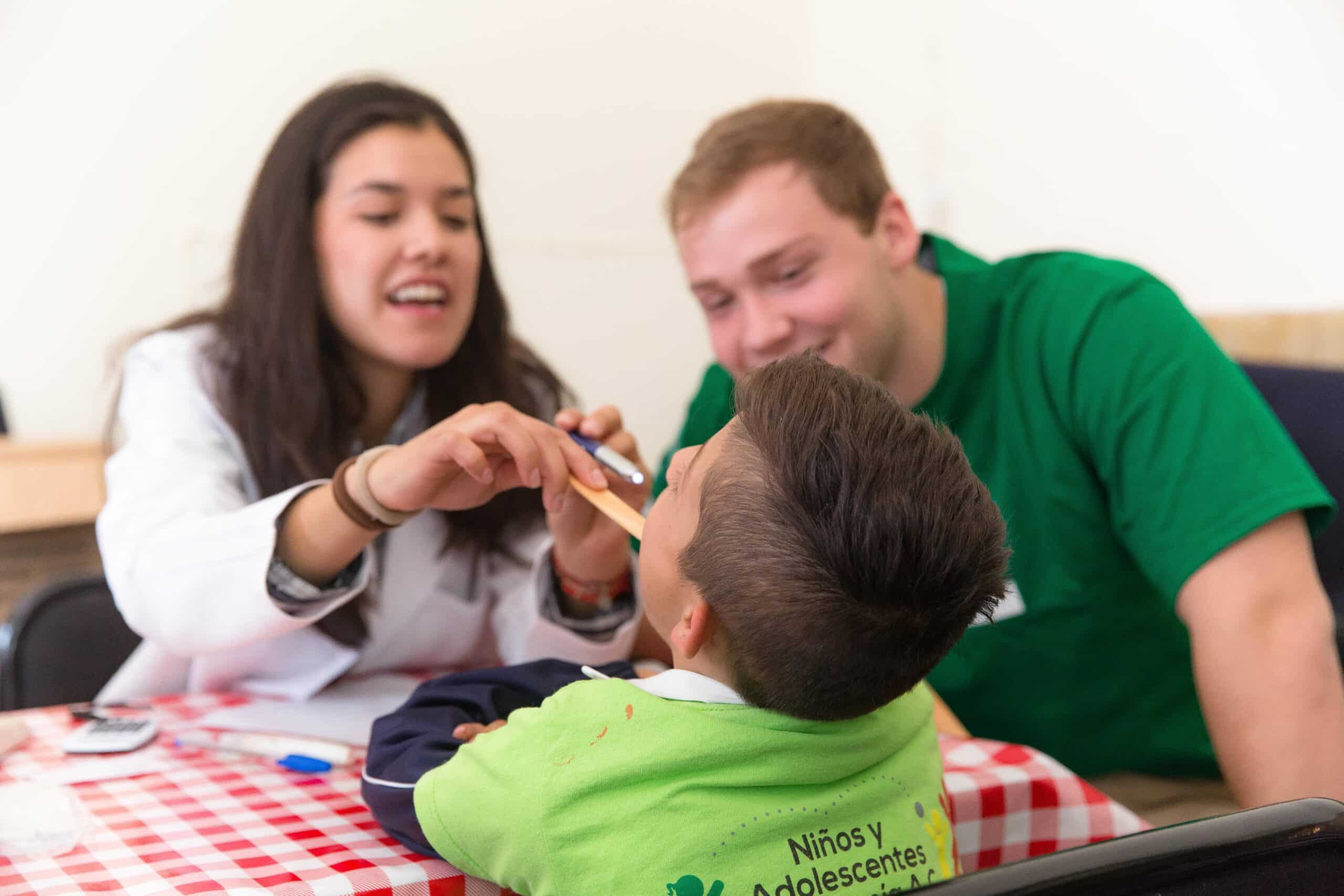 A local child has his teeth checked by two students doing a Dentistry internship in Mexico.