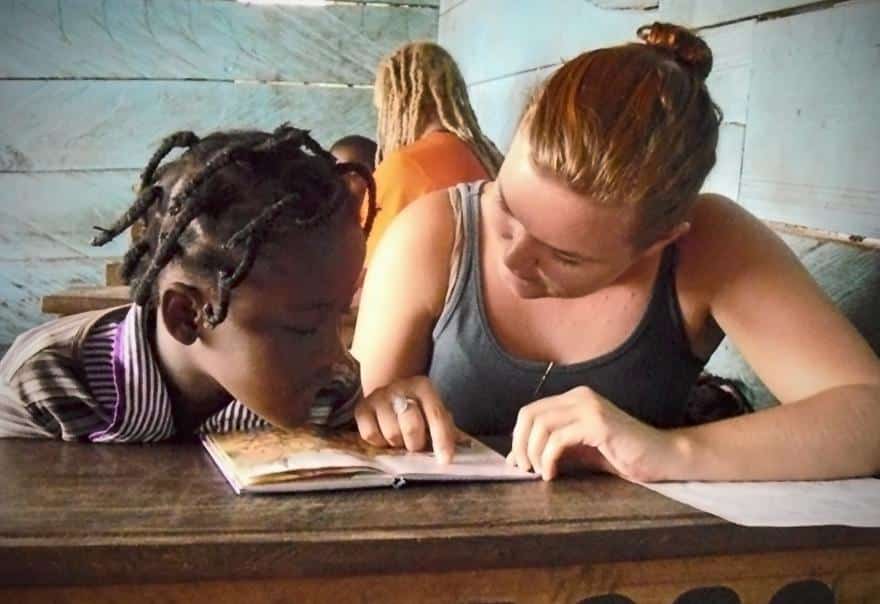 An intern is seen helping a young girl learn how to read and pronunciate whilst on her speech therapy internship in Ghana.