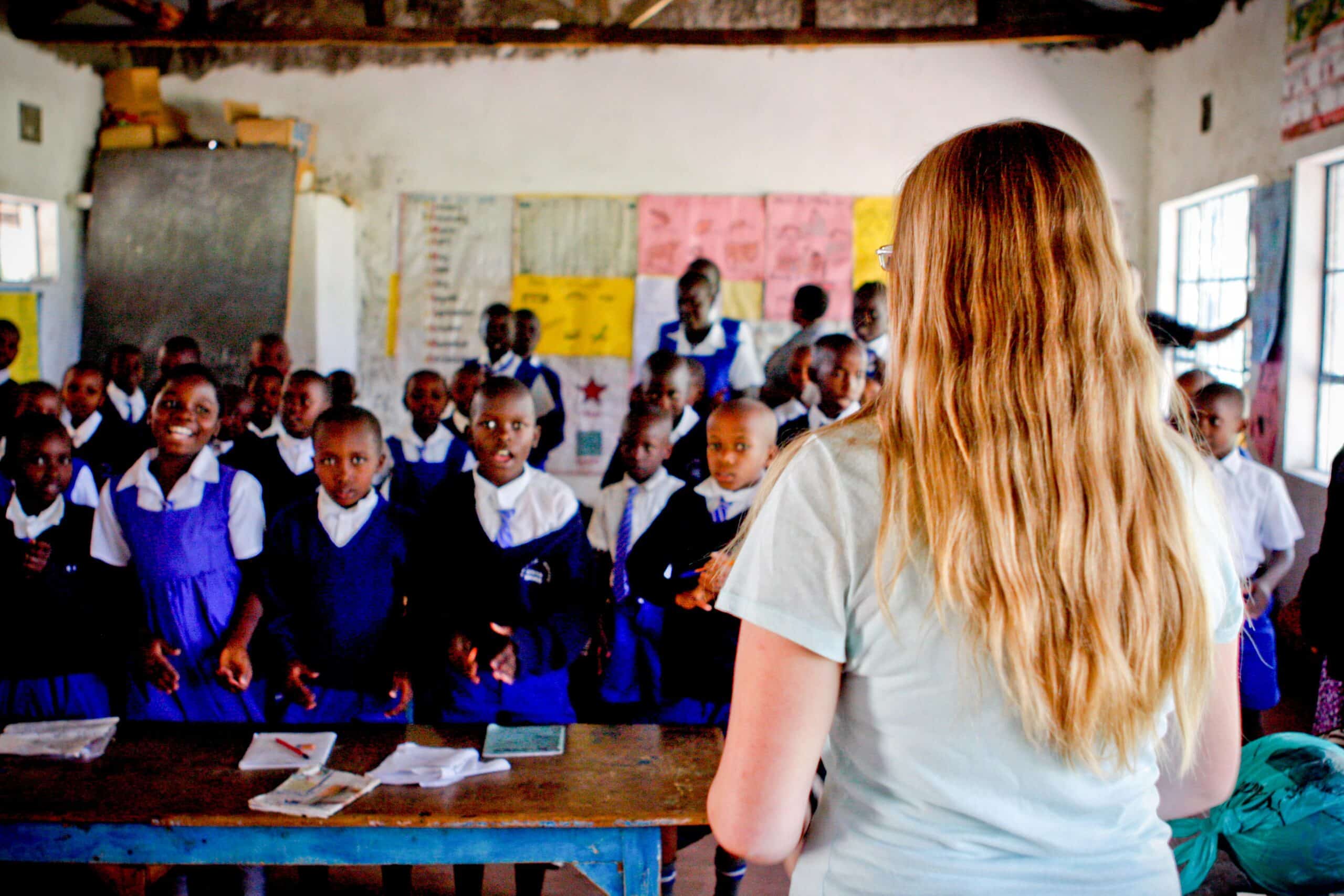 Students stand and listen to the Projects Abroad volunteer teaching them in Kenya