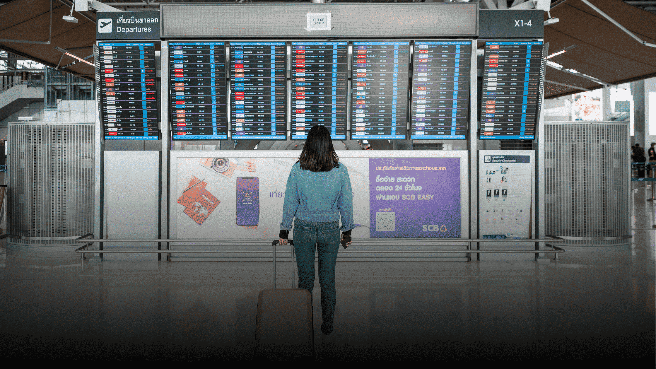 Woman standing in airport looking at flight information screens