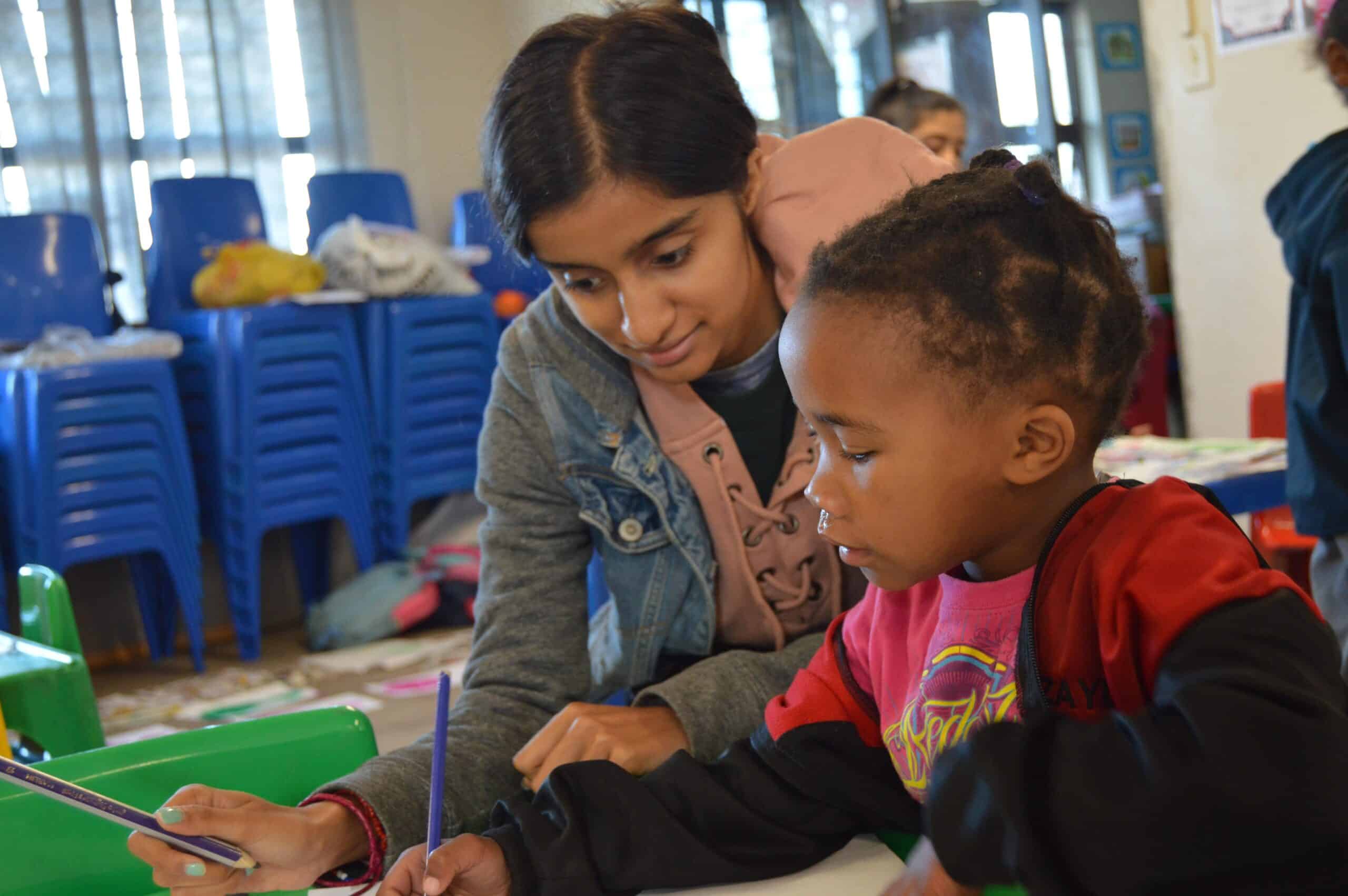 A Projects Abroad volunteer works with a child on a literacy exercise on one of our best volunteer abroad programmes UK. A teenager helps a child with a literacy exercise on one of our best high school volunteer abroad programmes.