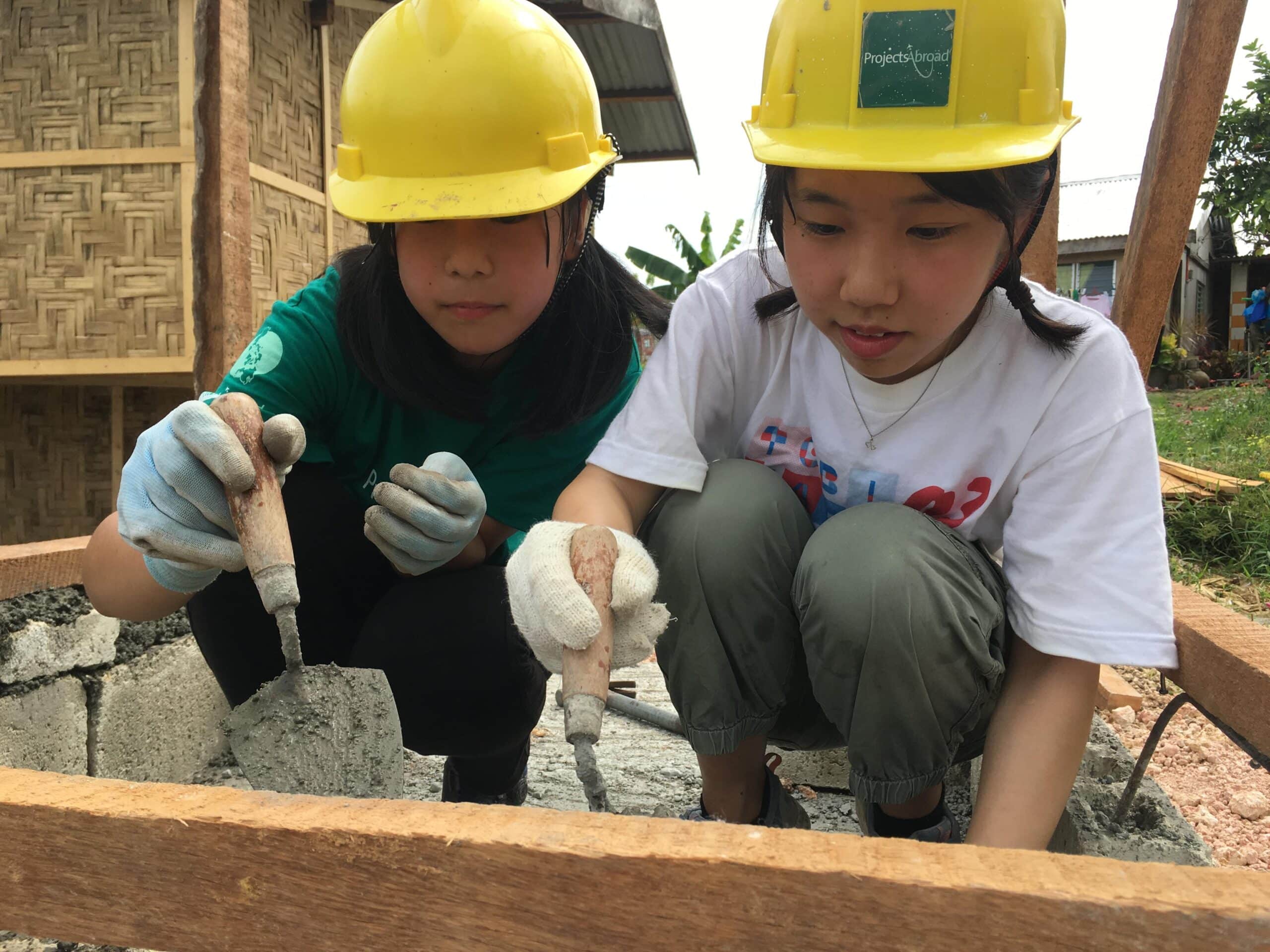 Two Building volunteers laying bricks on one of our best volunteer programmes in 2020. Two Projects Abroad volunteers building a house on one of our best volunteer abroad programmes.