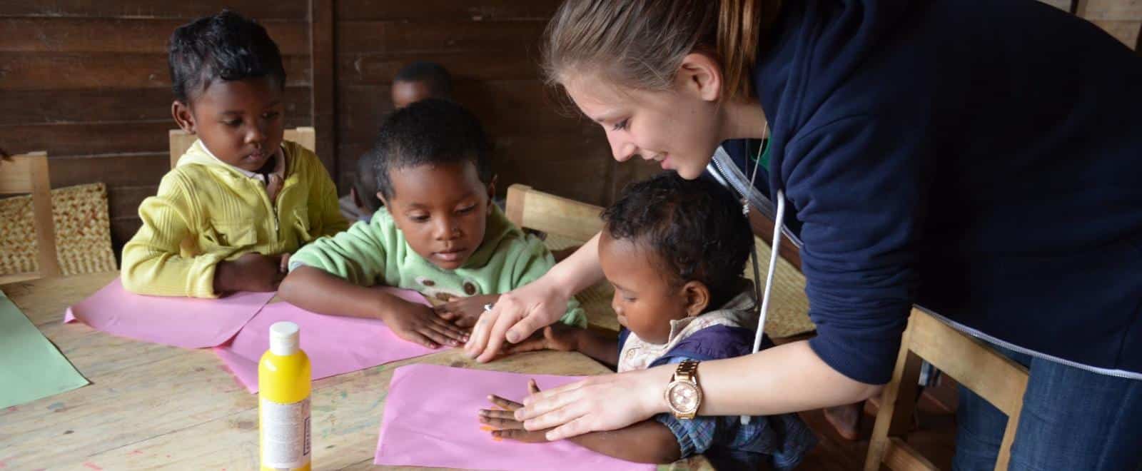 Children get help with an arts and crafts activity from a volunteer doing childcare work in Africa.